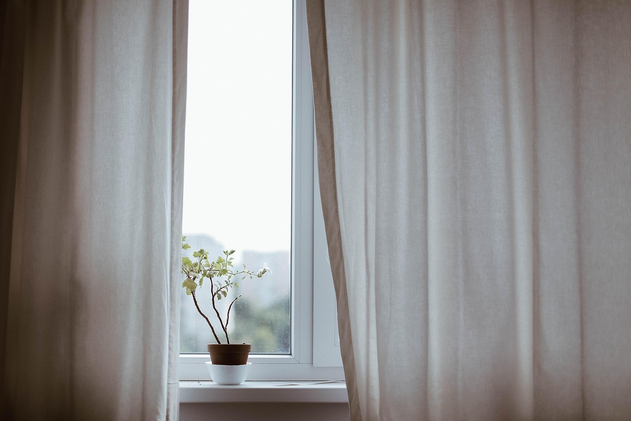 Oval soaking tub beside a window with plants